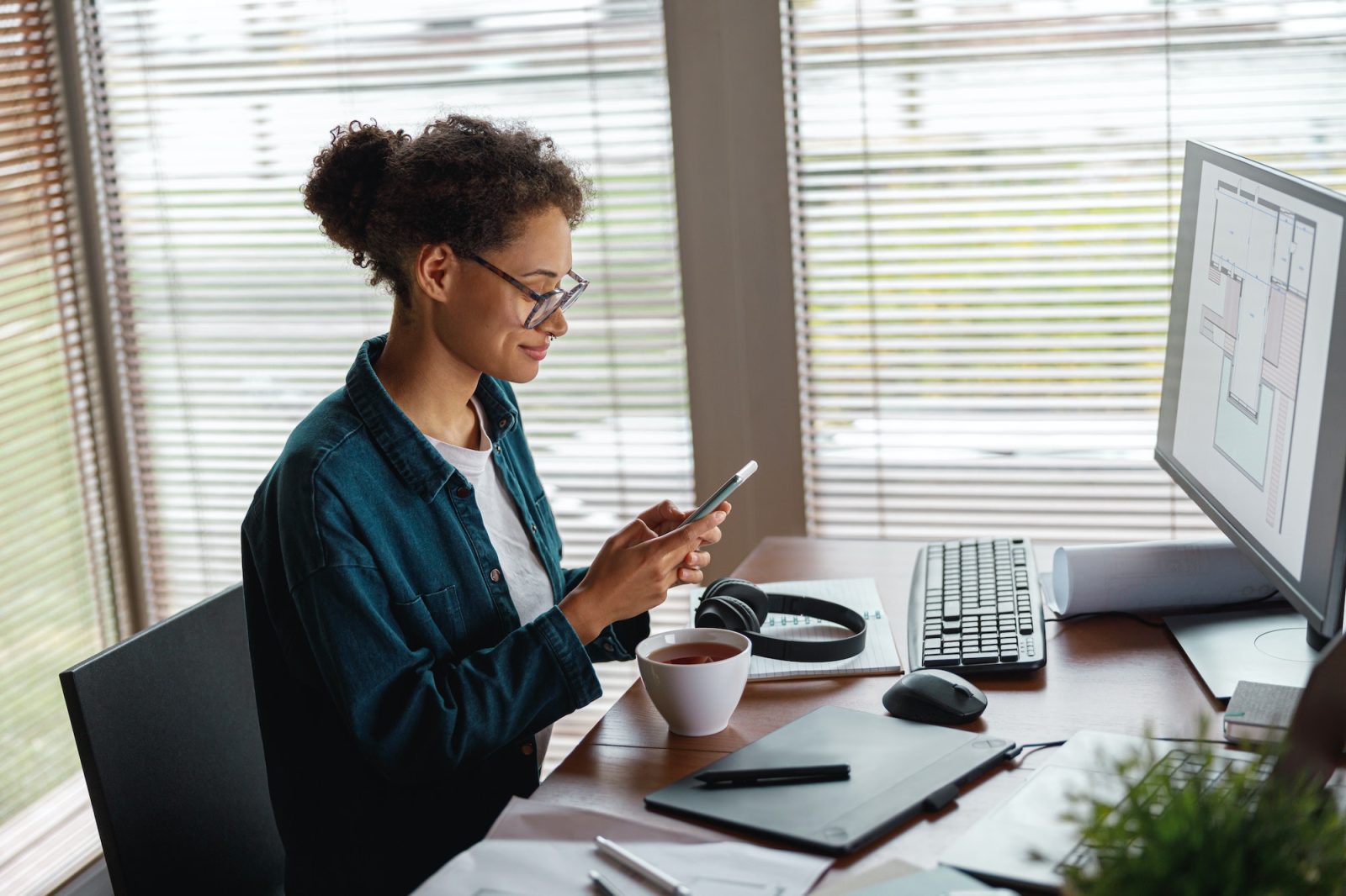 smiling woman interior designer holding smartphone during break at home office freelance concept